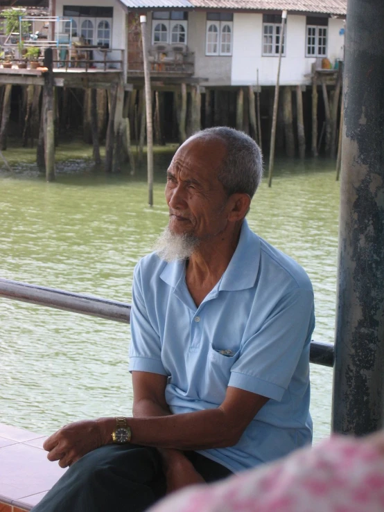 an older man is sitting at the end of the dock