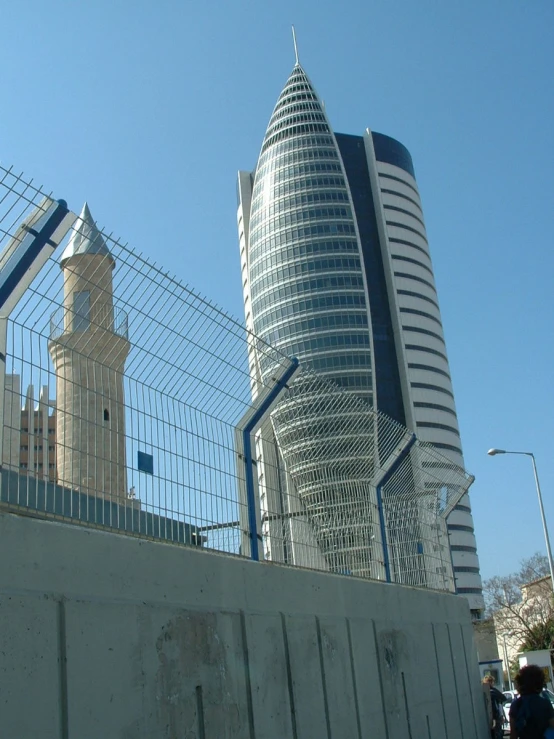 a tall building behind a fence next to tall buildings