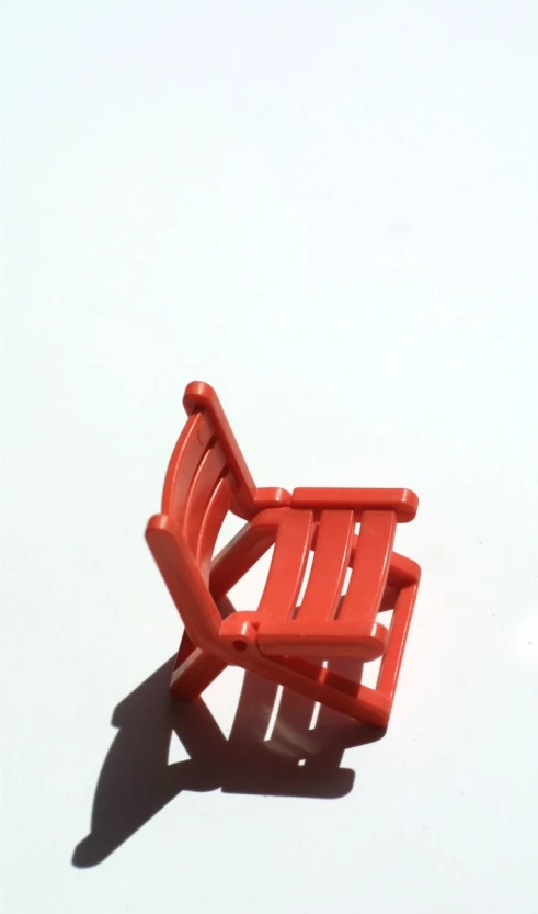 a red plastic chair is laying on a white surface