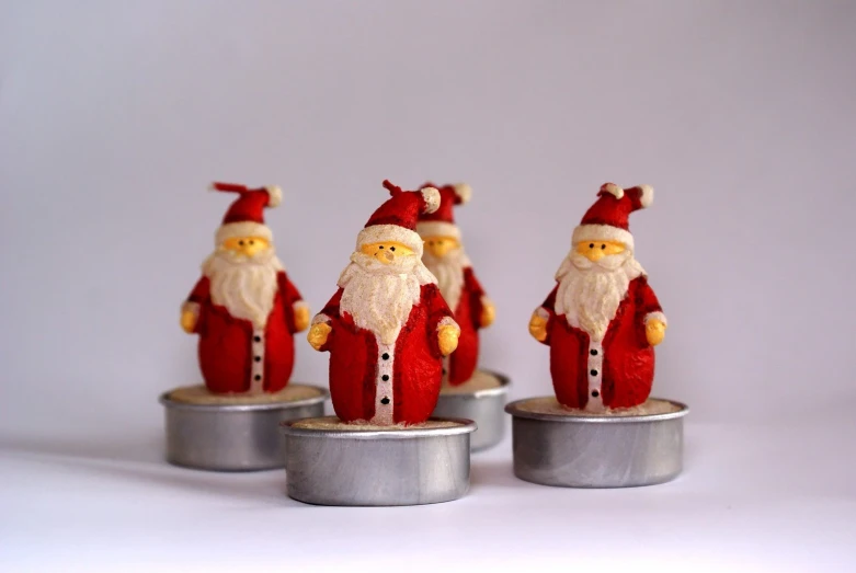 some little red santa claus figures sitting on some tins