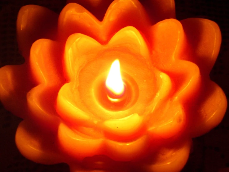 an orange lit candle that is on the surface