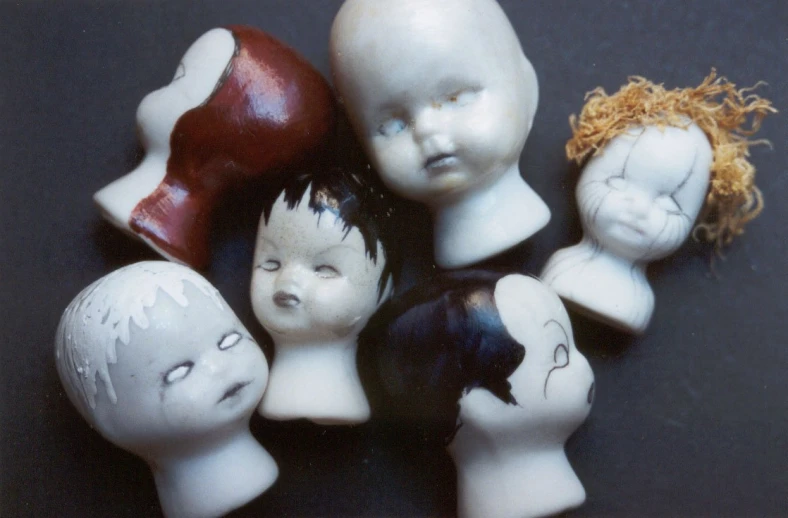 five white porcelain dolls and two orange plastic heads