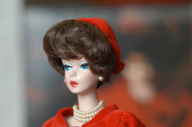 a doll wearing a red dress and pearl necklace