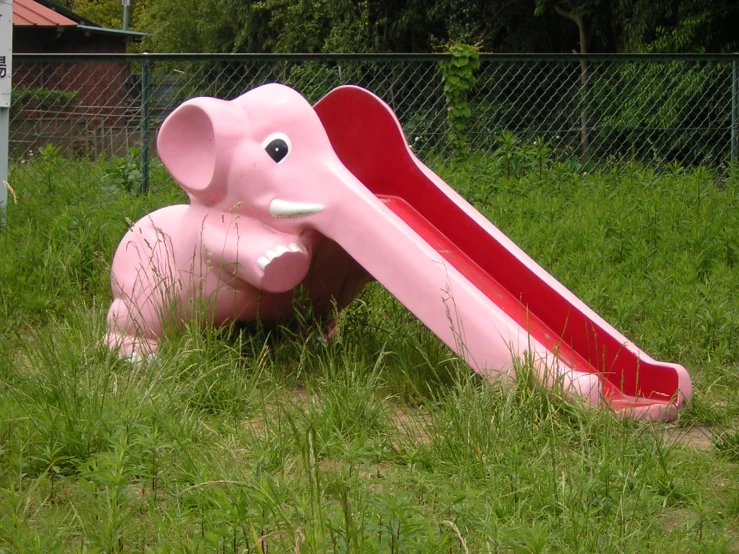 pink elephant playing with slide in grass area