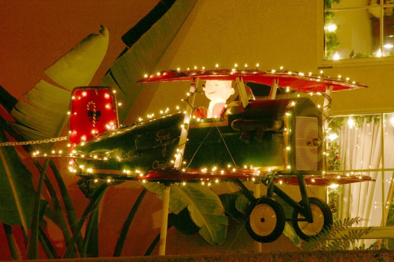 a train filled with christmas lights is parked near a house