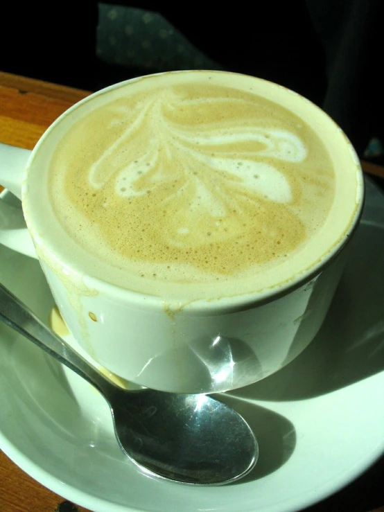 a plate that has a cup of coffee with some spoons