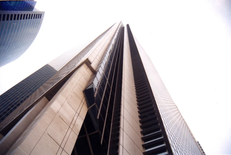 a tall brown building sitting in front of a cloud filled sky