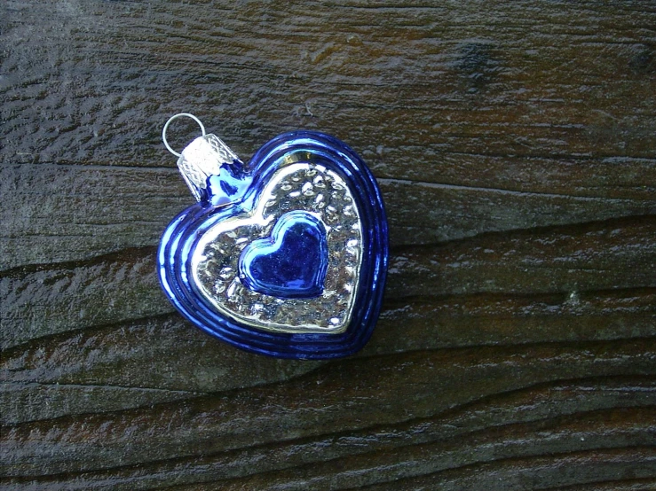 a blue heart shaped pendant sitting on top of a wooden table