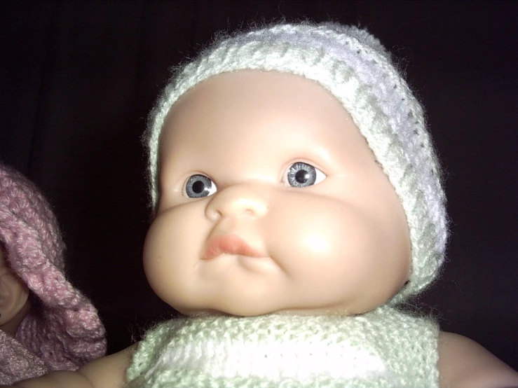 a close up s of a baby doll wearing a hat and scarf