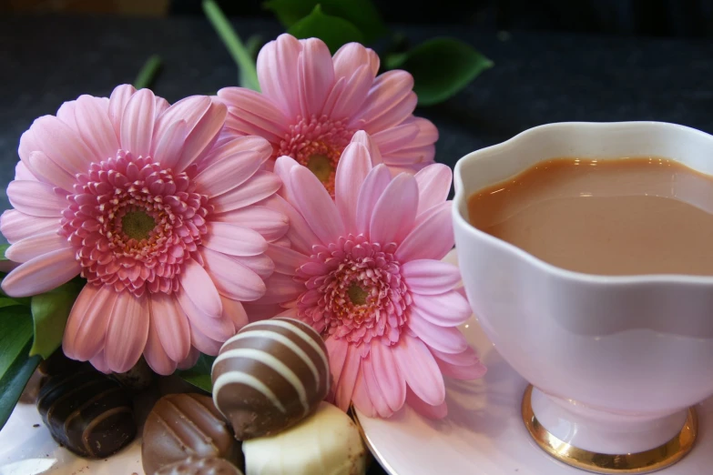 a plate of chocolates, flowers and a cup of coffee