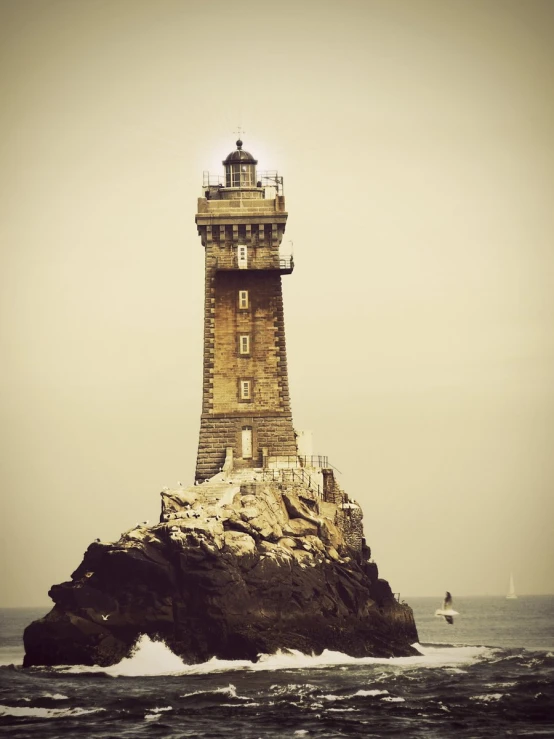 a light house is pictured on a rocky island in the ocean