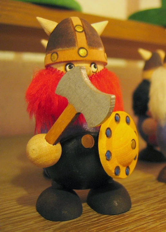 a toy viking, carrying a hammer, with two other toys