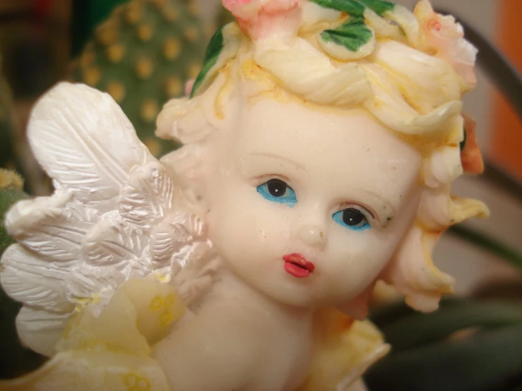 a white angel figurine sitting next to a plant