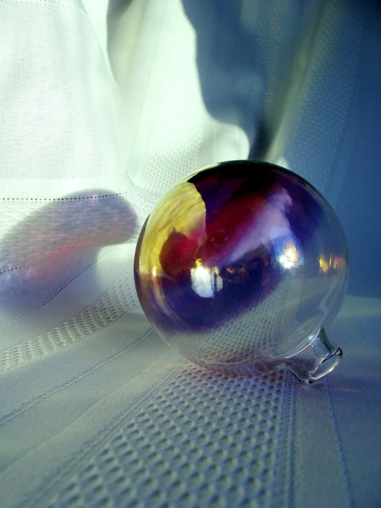 a shiny glass sphere is on the edge of a bed