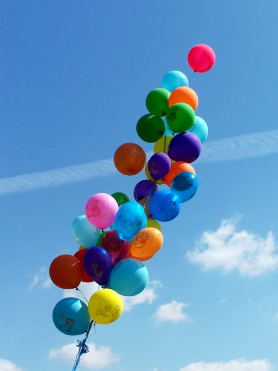 the rainbow colored balloons are sticking up high in the sky