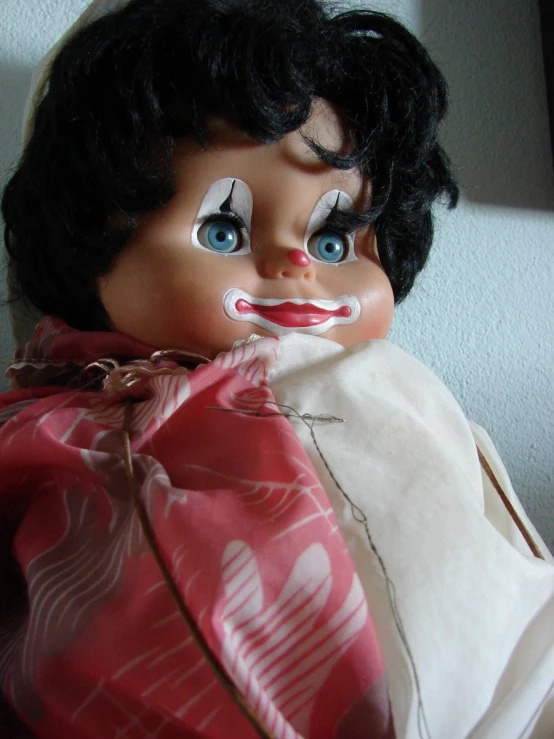 an old black doll has her head covered with fake makeup