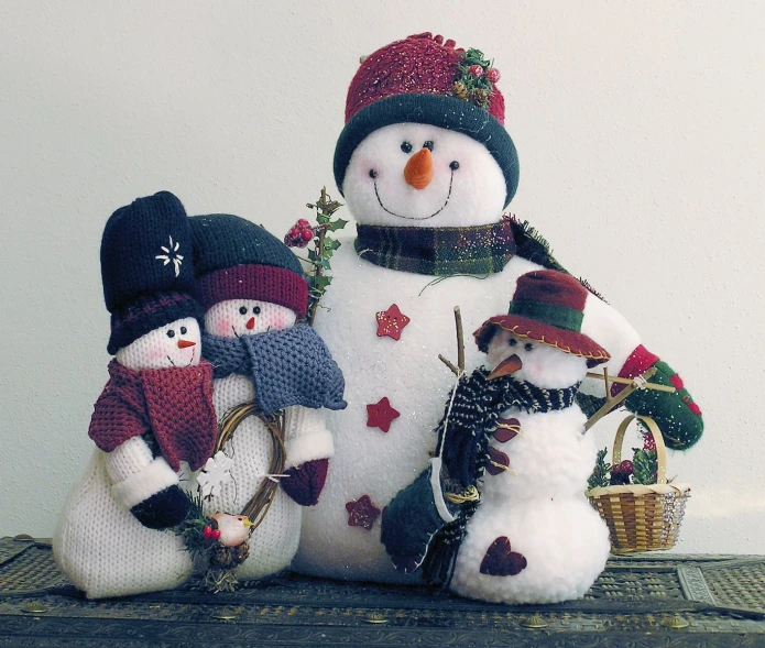 a knitted snowman and two small snowmen standing next to each other