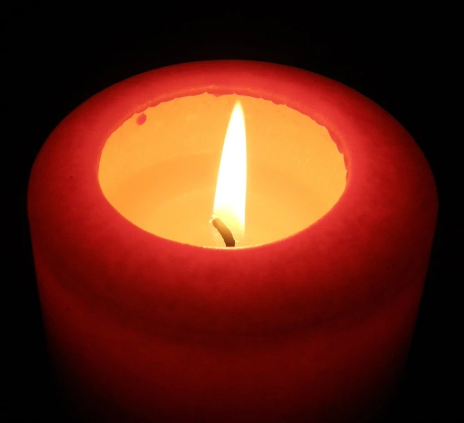 a lit red candle is lit in the dark