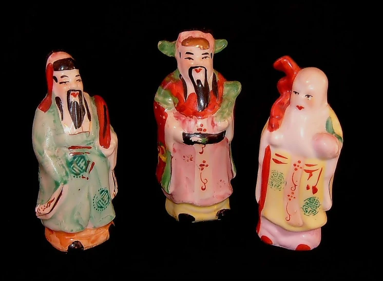 three ceramic figurines with asian characters painted on them