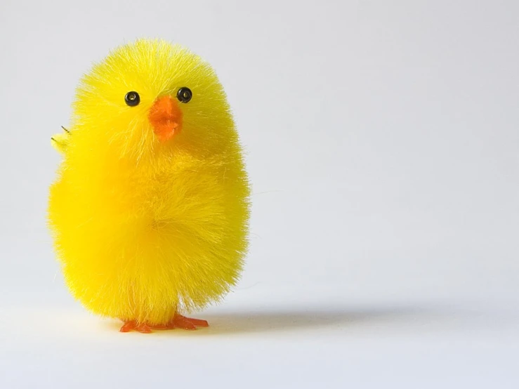 a yellow toy chicken sitting on top of a white surface