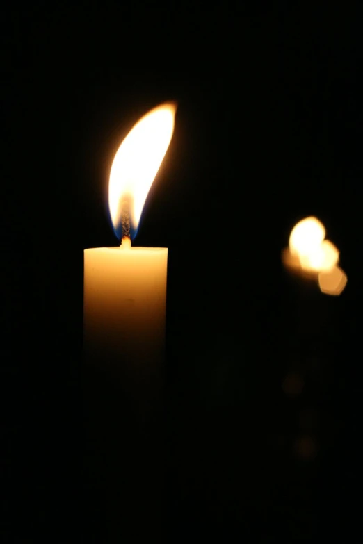 a candle burning brightly in the dark with a lightening