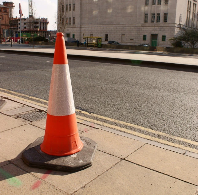 a orange cone sitting on the side of the road