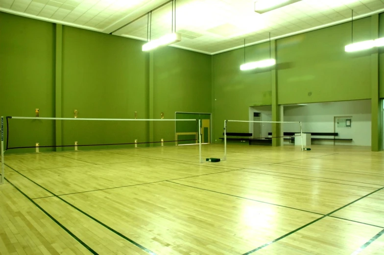 a large gymnasium with some badminton equipment and a net