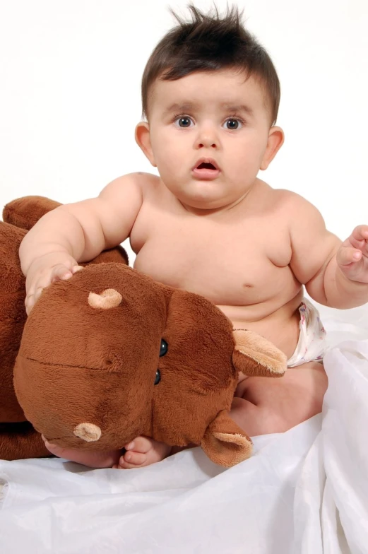 an infant in diapers is sitting with two stuffed animals