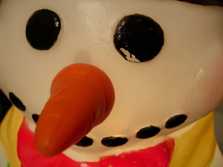 the nose of a snow man wearing a shirt and a noseband with a carrot sticking out of it