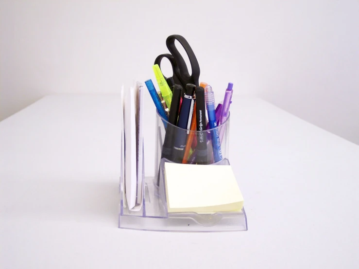 the pen holder is made from plastic and holds several pens, papers, and marker markers