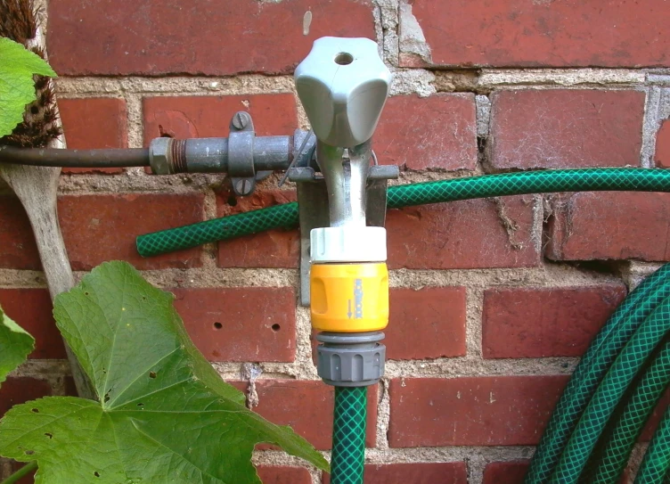 green hoses attached to a red brick wall