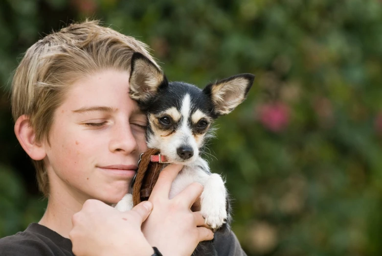 a young man holding his puppy on his lap