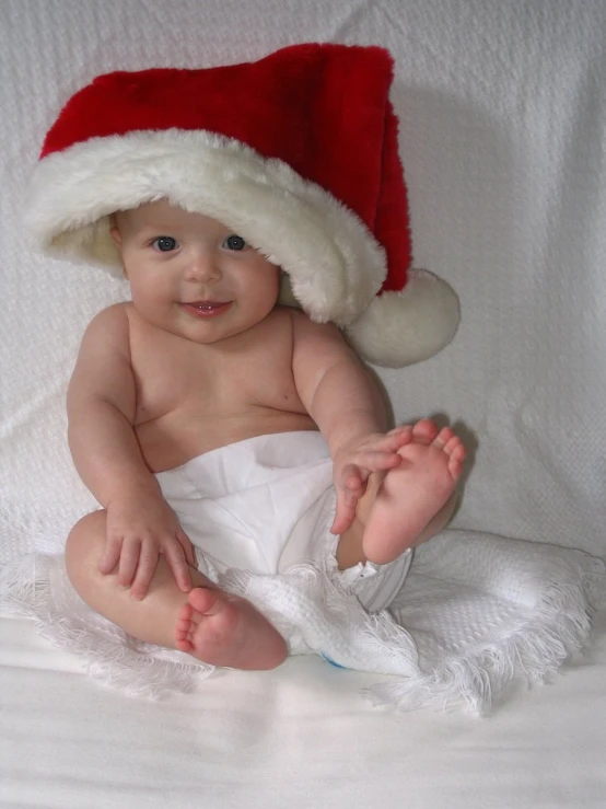 a baby sitting down wearing a christmas hat