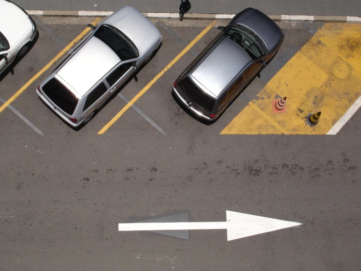 parking lot with two car parked in the lane and an arrow pointing to the left