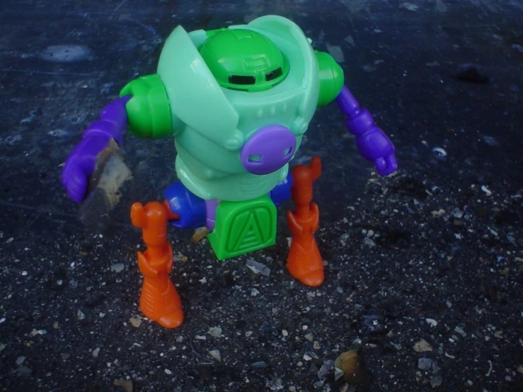a toy robot on the ground next to a pair of red orange boots