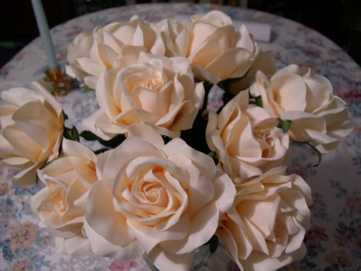 an arrangement of four pink roses sitting on a round table
