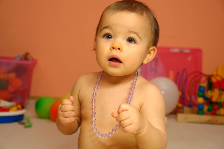 a young child in a small pink necklace on top of a table