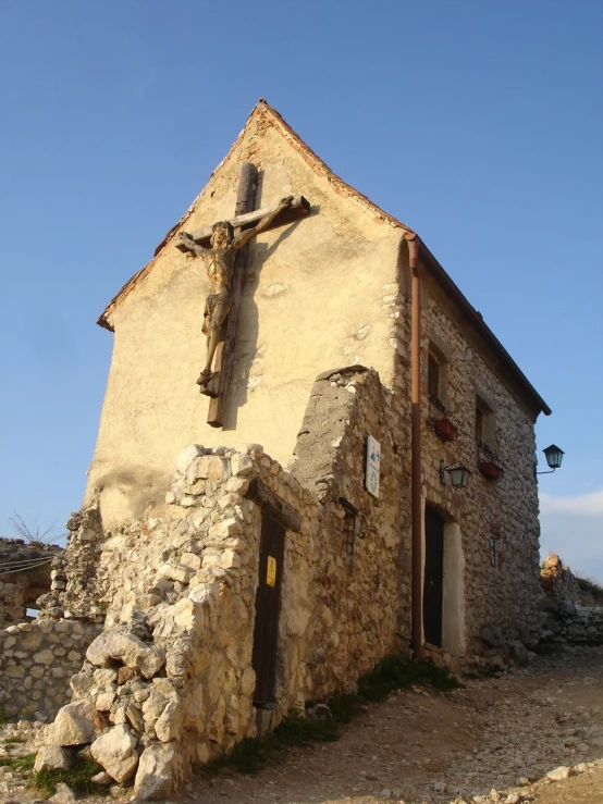 a stone house with a cross above it on the front