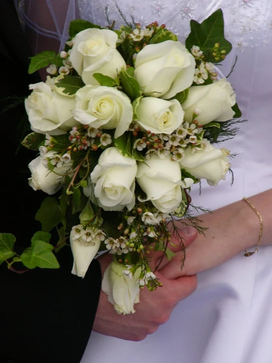 a bride holding a bouquet of white roses