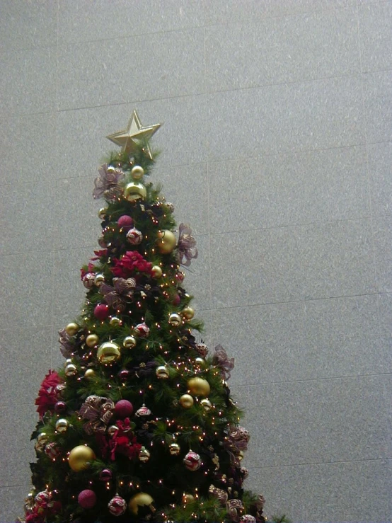 a very pretty and colorful christmas tree near some wall