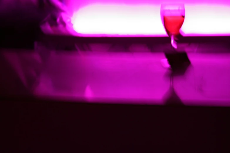 a wine glass is shown in front of pink lights