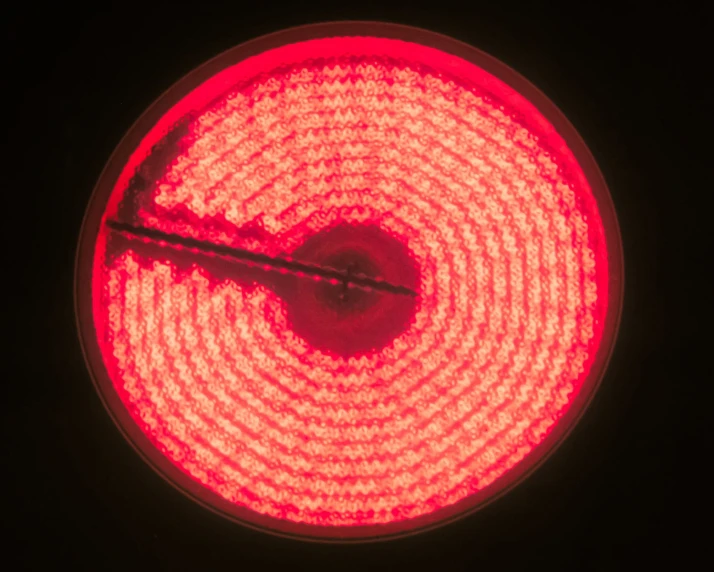 a red street light in the dark with a wire at its bottom