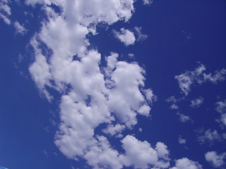 the airplane is flying in the air with clouds above it