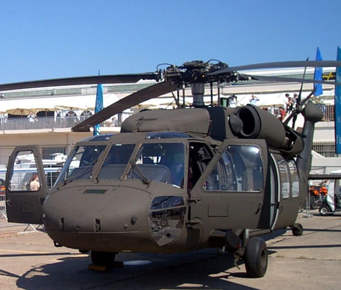 a military helicopter sits parked at the airport