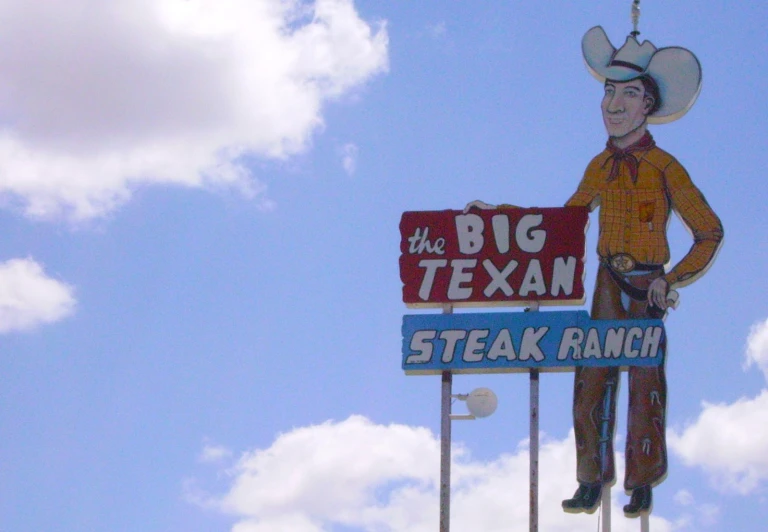 a big tex sign hanging from the side of a building