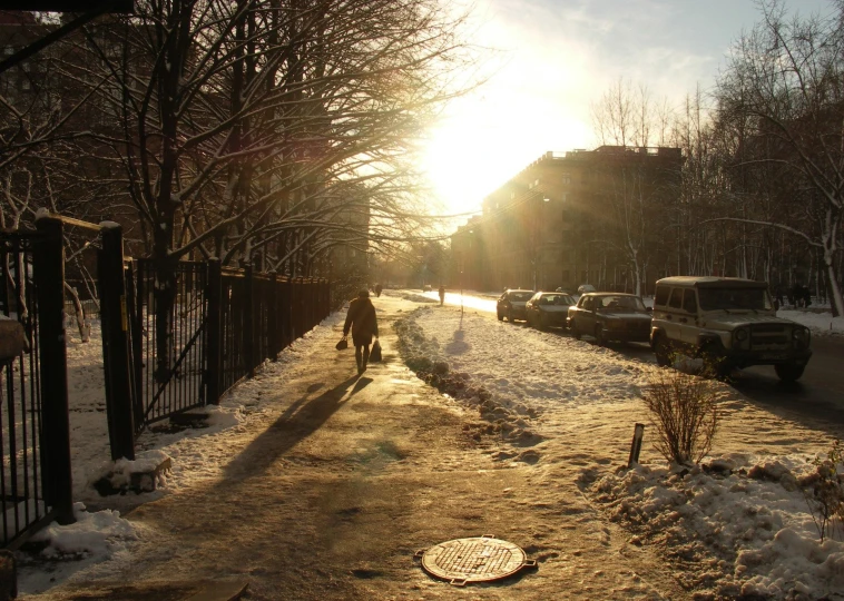 the sun is setting and the sidewalk covered in snow