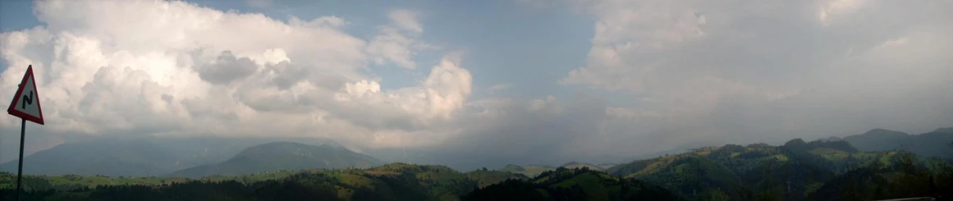 the clouds are above some mountains and trees