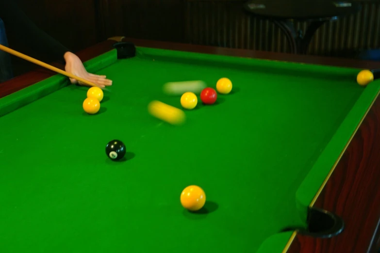 a person hitting balls with a cue in a game room