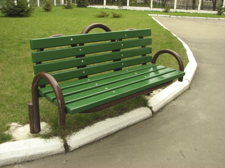 there is a green bench outside by the road