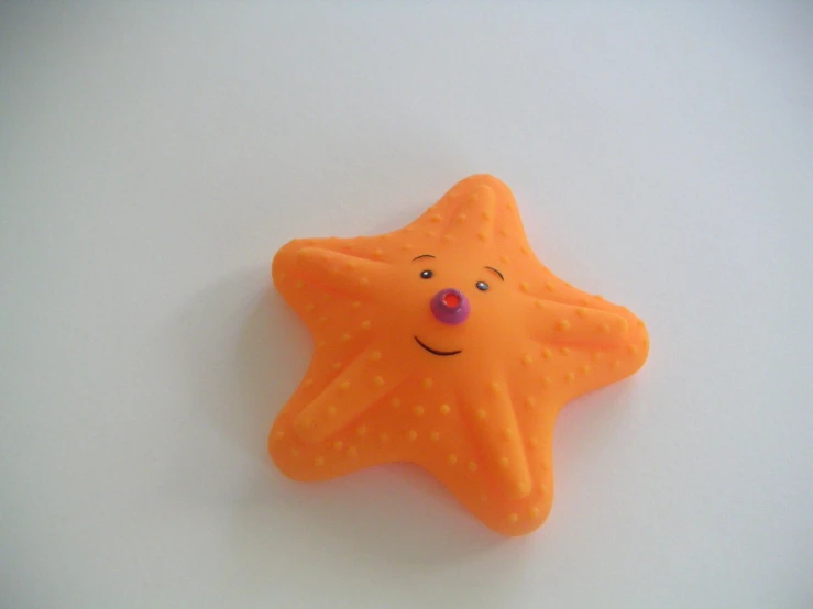 there is a orange starfish brooch with smiley face on it